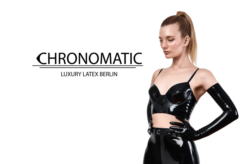 Model trägt ein Midi Kleid mit hohem Kragen und einem Berét aus Latex in dunkelrot.